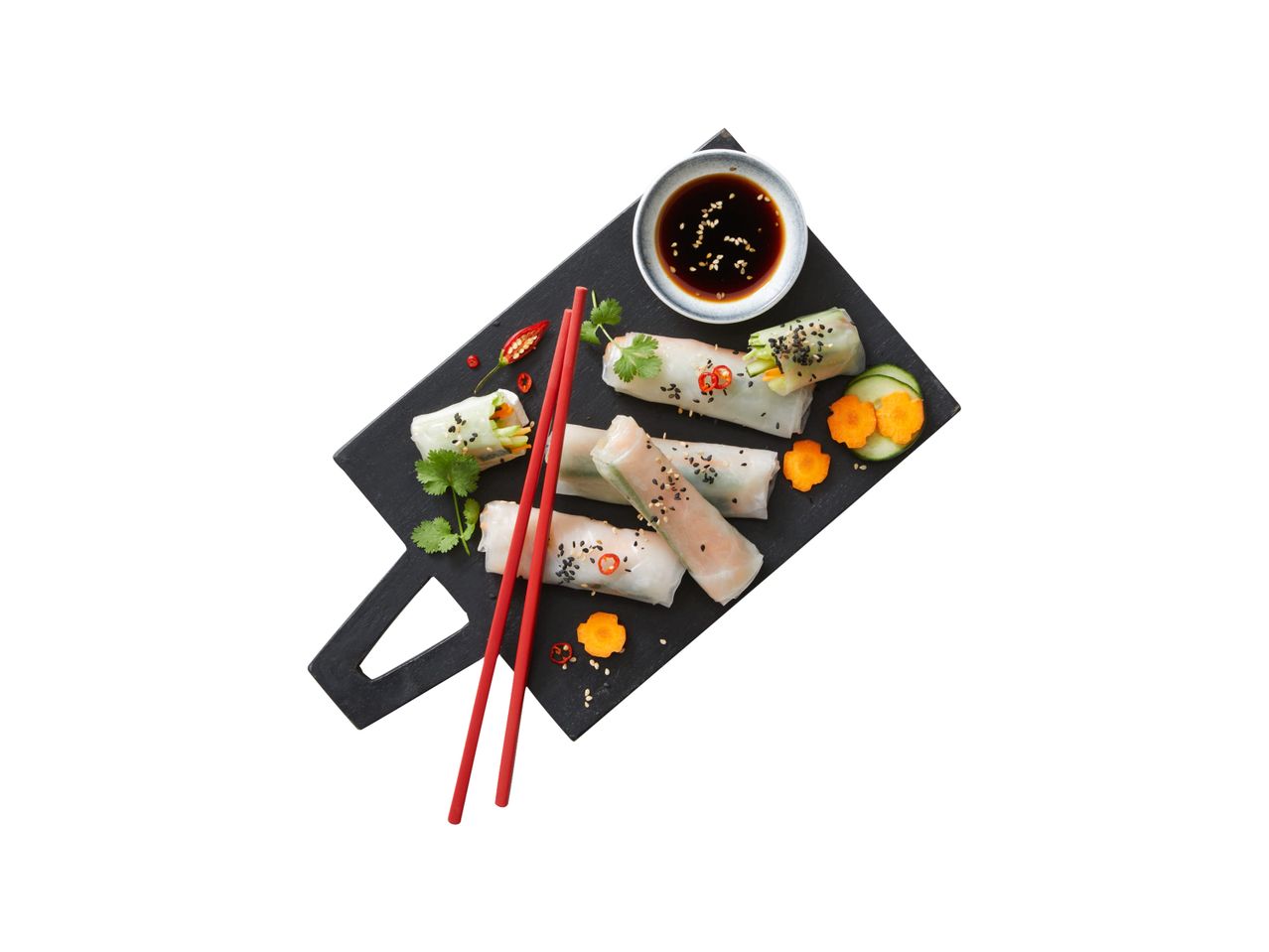 Fresh spring rolls arranged on a black slate with dipping sauce and chopsticks.