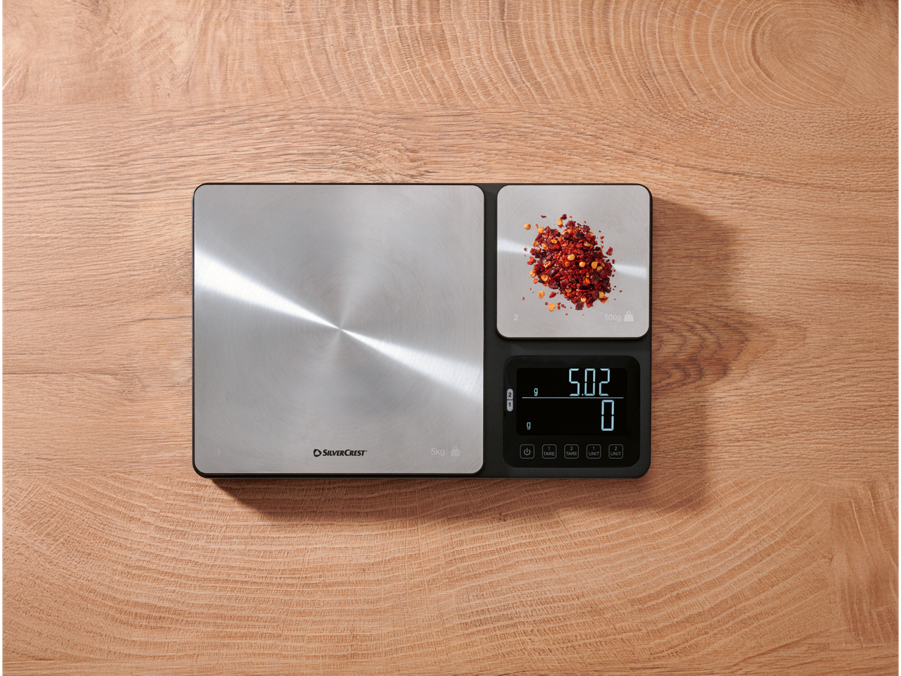 Balança de cozinha com duas superfícies de pesagem, uma mostrando 5,02g de flocos de chili.