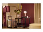 A modern living room with black metal side tables, a vase of flowers, and a glowing lamp.