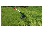 Electric string trimmer cutting grass and weeds.