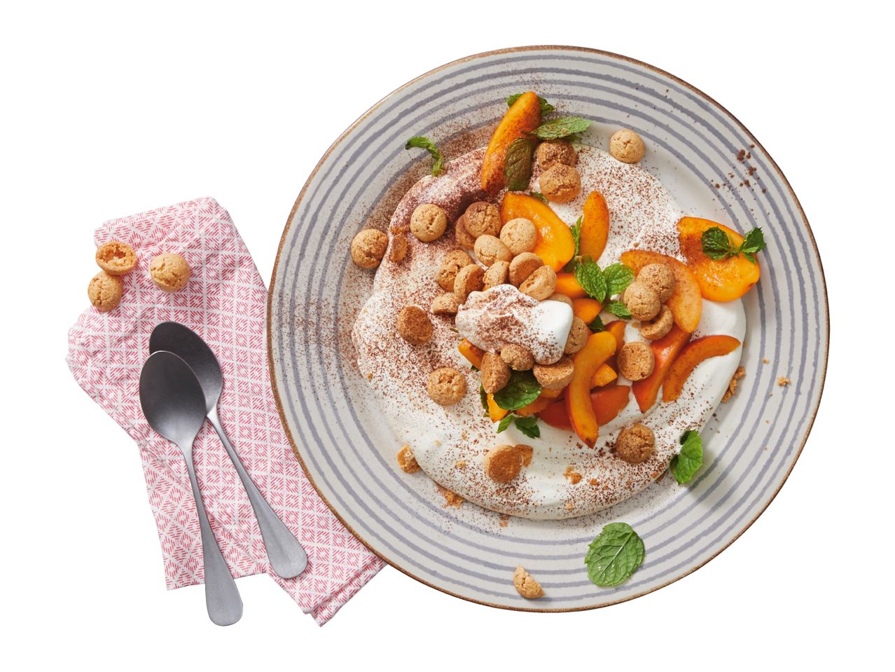 Dessert with whipped cream, sliced apricots, amaretti biscuits, and mint on a striped plate.