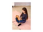 Girl playing with a plush toy on a pink rug.