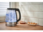 SILVERCREST® Colour Changing Glass Kettle boiling water on a kitchen counter with cookies.