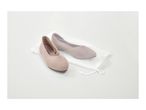 Two beige knitted ballet flats, one inside a white mesh laundry bag, on a white surface.