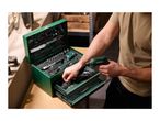 Man selecting a bit from a green tool box with a cordless screwdriver in hand.