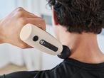 A person using a massage gun on their neck.