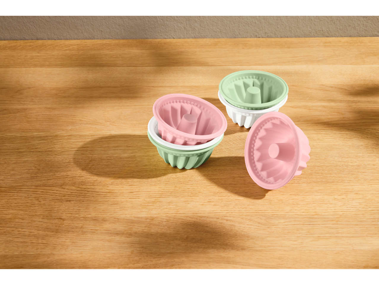 Silvercrest® silikonski kalupi u roze, zelenoj i beloj boji na drvenoj površini.