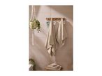 Beige towels hanging on a wooden rack and stacked on a stool, with a hanging plant.