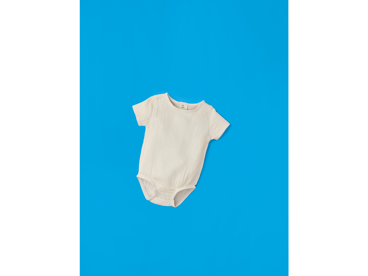 LUPILU bež muslin bodi za bebe na plavoj pozadini.