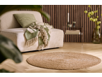 Beige armchair with green cushion and blanket, jute rug, and wooden slatted wall.
