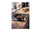 Cast iron grill pan with meat skewers on a gas hob in a kitchen setting.