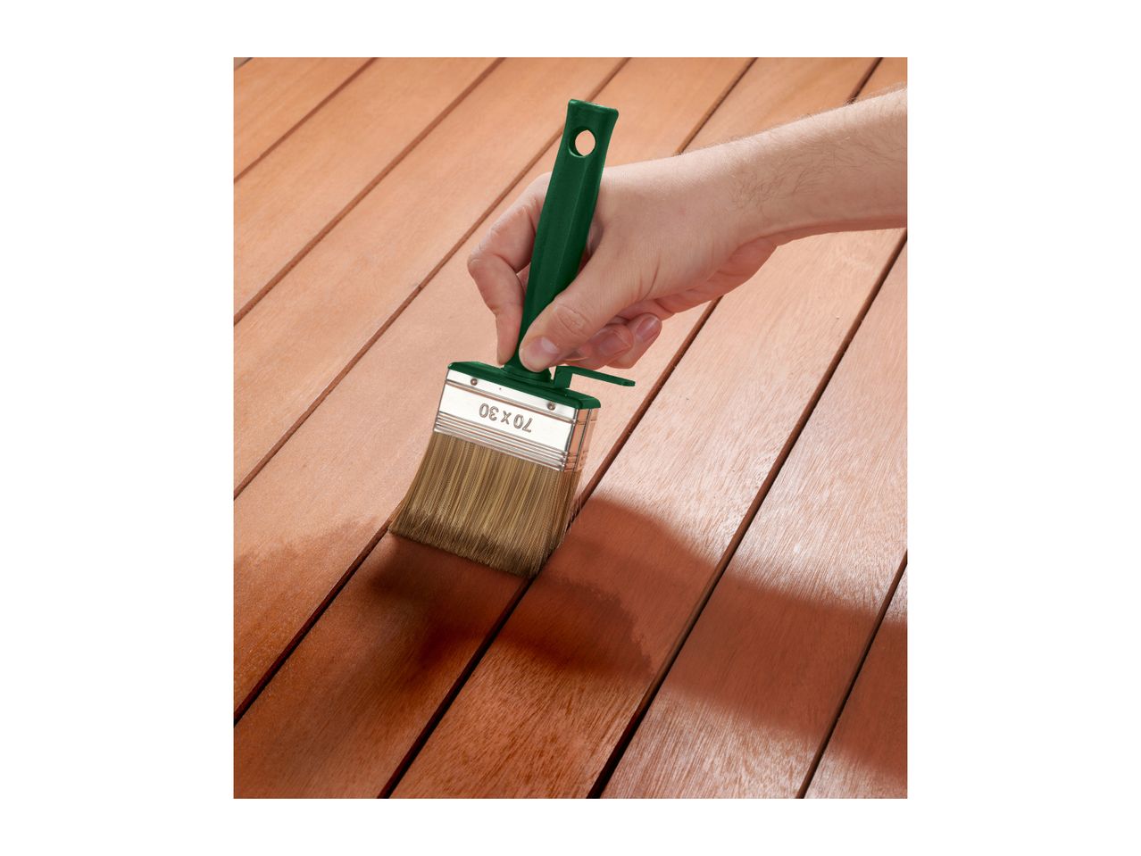 Hand applying wood stain with a brush to wooden planks