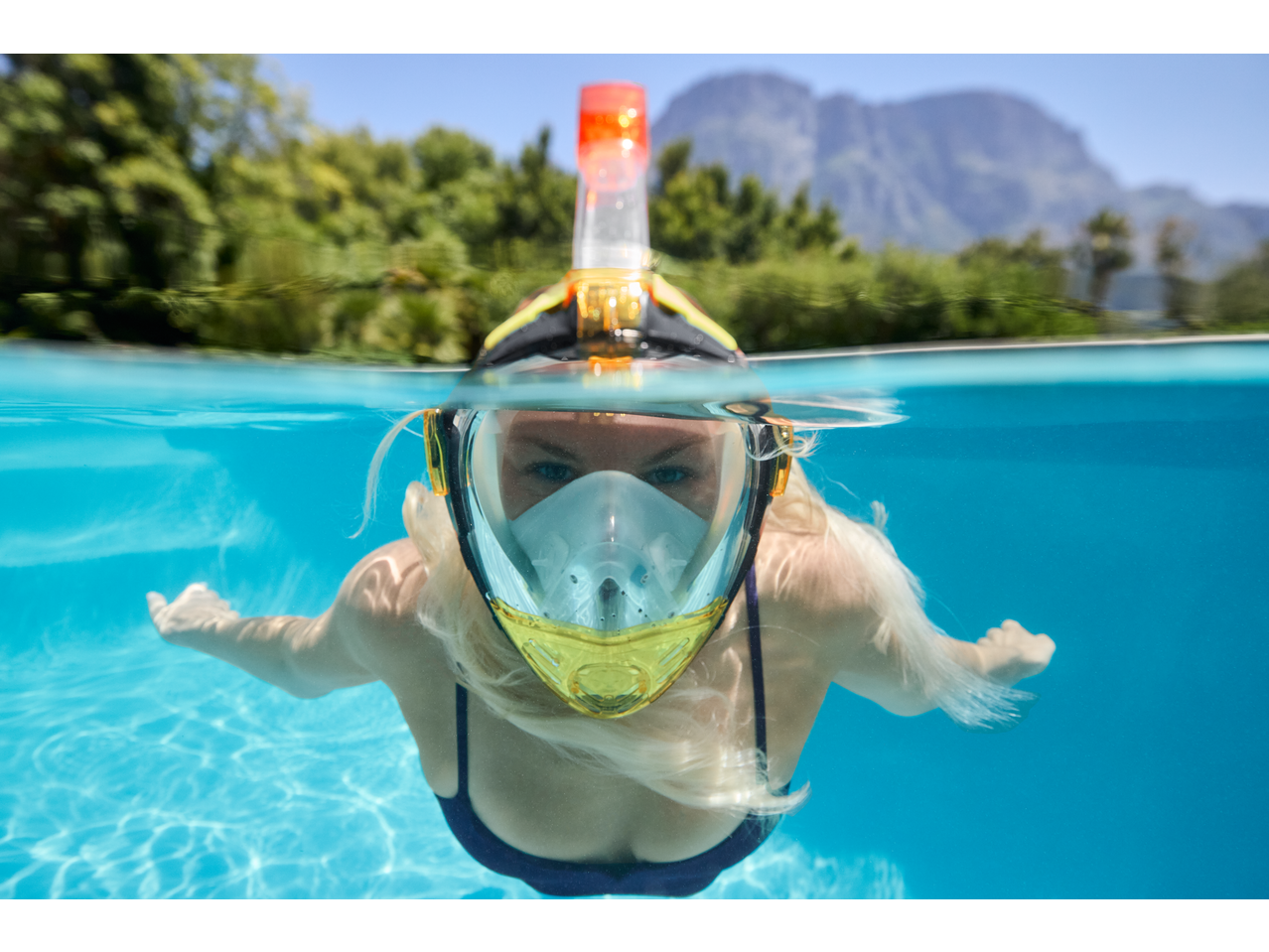 Woman wearing a CRIVIT Premium Snorkel Mask underwater in a pool.