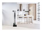 Cordless stick vacuum cleaner charging on its stand in a modern kitchen.