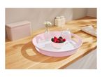 Pink serving tray with berries, water, and flowers on a wooden counter.