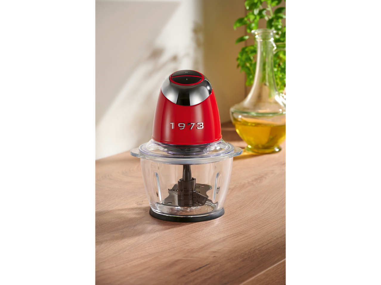A red and black Silvercrest mini chopper with a clear bowl sits on a wooden surface.