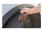 Hand holding a tire tread depth gauge on a car tire