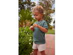 Lupilu boy in green T-shirt and shorts, holding a daisy.