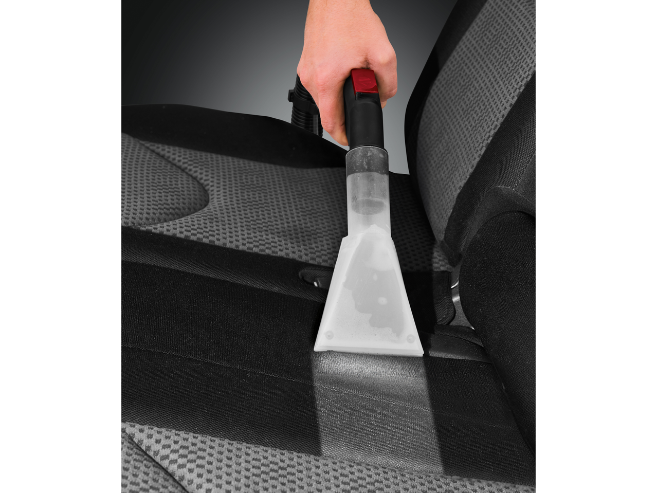 Osoba čisti autosjedalicu Parkside® usisavačem za pranje.