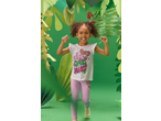Menina sorridente com t-shirt branca e leggings cor-de-rosa, rodeada por folhas de papel verdes.