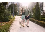 Un cuplu se plimbă cu câinele lor golden retriever într-un parc.