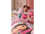 A child in Gabby's Dollhouse pyjamas laughs while sitting on a bed with matching bedding.