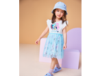 Young girl in a white and blue tulle dress with cartoon characters, wearing a denim bucket hat and purple sandals.