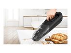 Handheld vacuum cleaner cleaning breadcrumbs from a kitchen counter.