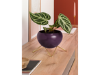 Vaso de flores roxo com suporte dourado em móvel de madeira.