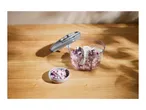 A manual food chopper with diced red onions on a wooden surface.