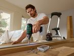 Ένας άντρας χρησιμοποιεί ένα τρυπάνι Bosch για να βιδώσει σε ξύλινη επιφάνεια.