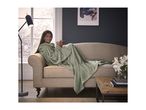 A woman in a green hooded blanket on a sofa, holding a mug.
