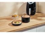 Mini pizzas, bolo e espetos em uma bancada de cozinha ao lado de uma fritadeira a ar.