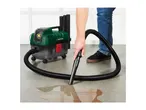 Person using a wet and dry vacuum cleaner to clean up a spill on a concrete floor.