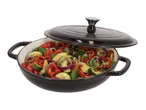 Black cast iron casserole dish with lid, filled with colorful roasted vegetables.
