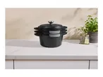 Stack of three black cast iron pots with lids on a kitchen counter next to a potted plant and salt and pepper shakers.