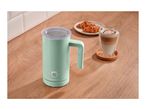 Mint green milk frother with a latte and croissants on a wooden surface.