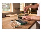 Person repairing a laptop with a precision screwdriver set on a wooden table.