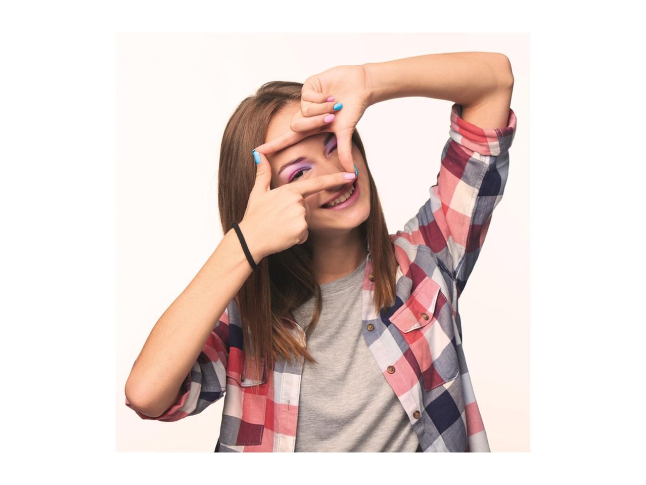 Young woman in a plaid shirt making a frame with her hands, smiling.