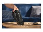 Handheld vacuum cleaner cleaning crumbs from a wooden table