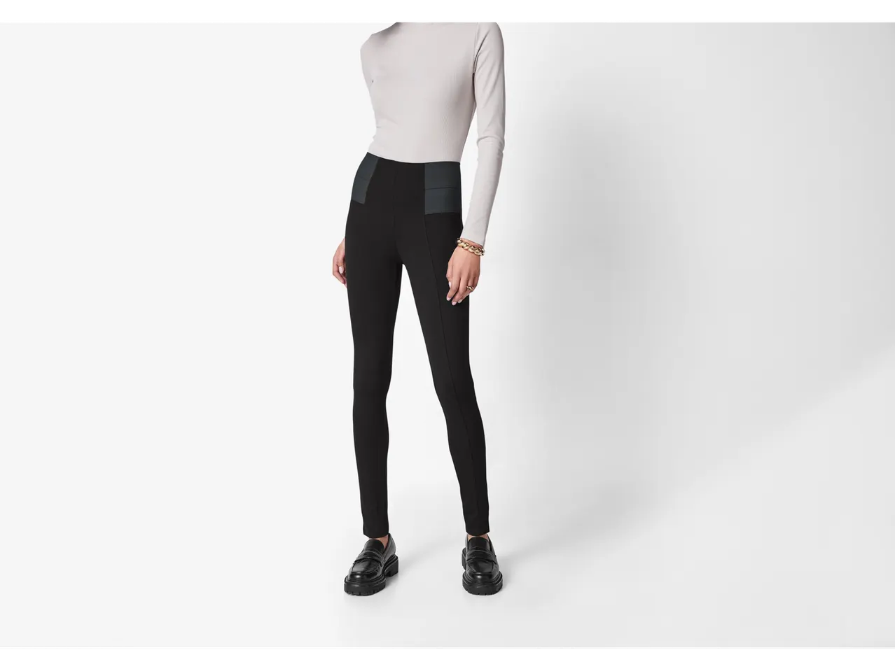 Femeie în jeggings modelatori negri Esmara și maletă gri deschis.