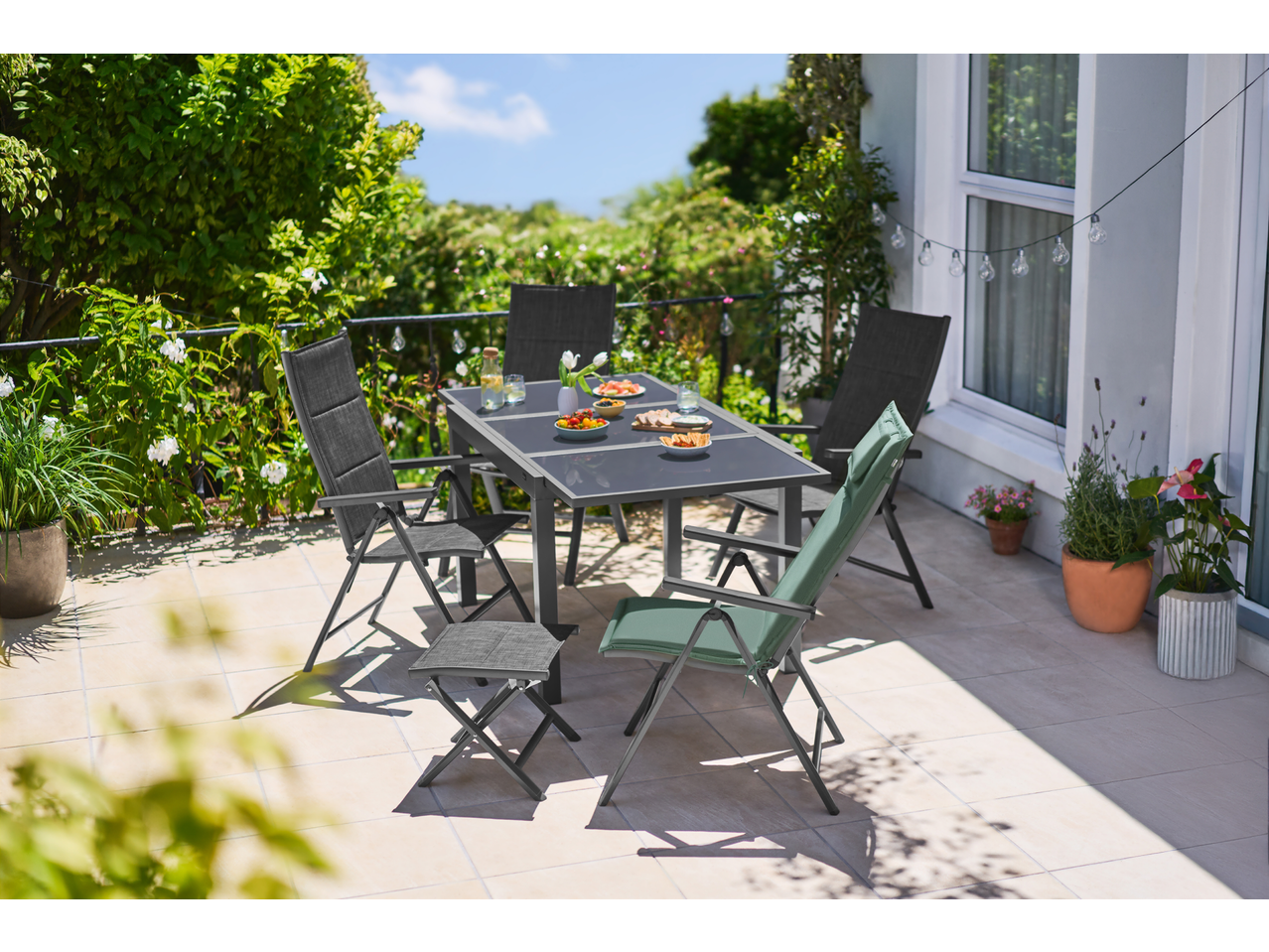 Livarno Solar Bulb String Lights illuminate a patio with a dining table and chairs.