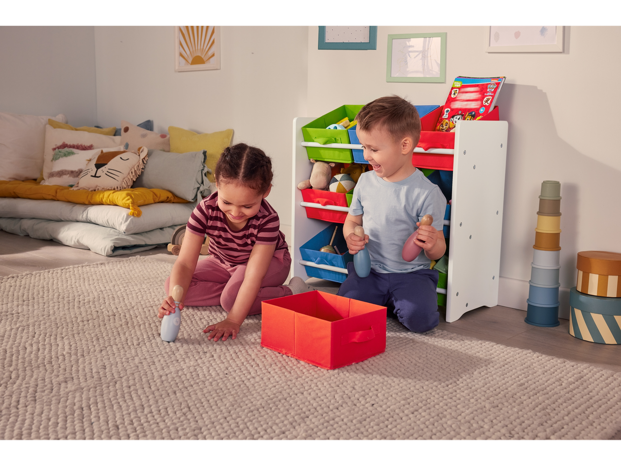 Crianças brincando ao lado de uma estante de arrumação LIVARNO home com caixas coloridas.