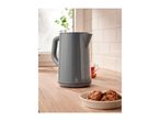 A grey electric kettle on a wooden kitchen counter with cookies and a cup of tea.