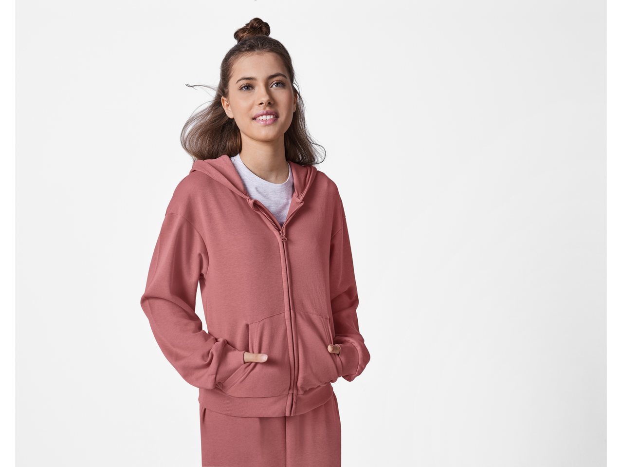 Žena nosi roze duks sa kapuljačom i donji deo trenerke.