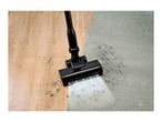 Vacuum cleaner head cleaning dirt from a wooden floor and a light grey carpet.