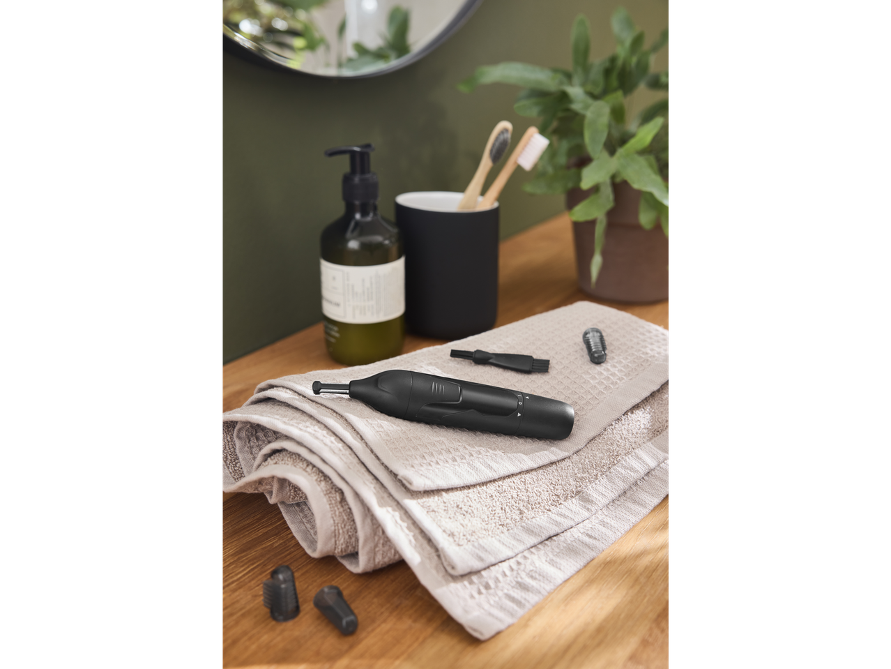 A black nose and ear hair trimmer with accessories on a towel in a bathroom setting.