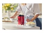 A person holding a bowl of popcorn next to a red popcorn maker on a kitchen counter.