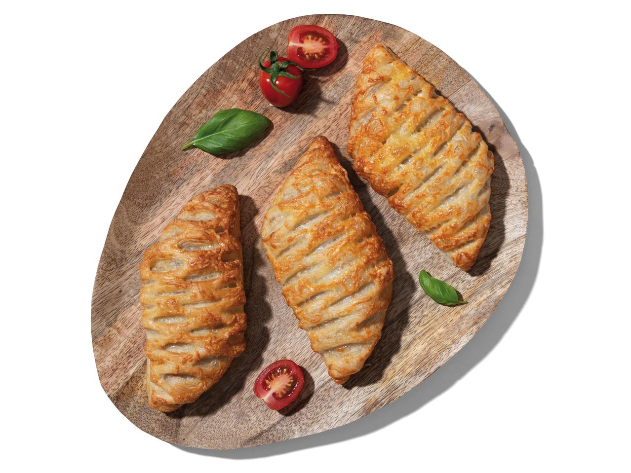 Három sajtos sütemény fa deszkán cseresznye paradicsommal és bazsalikommal.