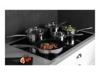 Stainless steel cookware set on an induction hob, with a frying pan cooking meat and figs.